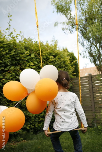 Girl with balloons sitting on swing