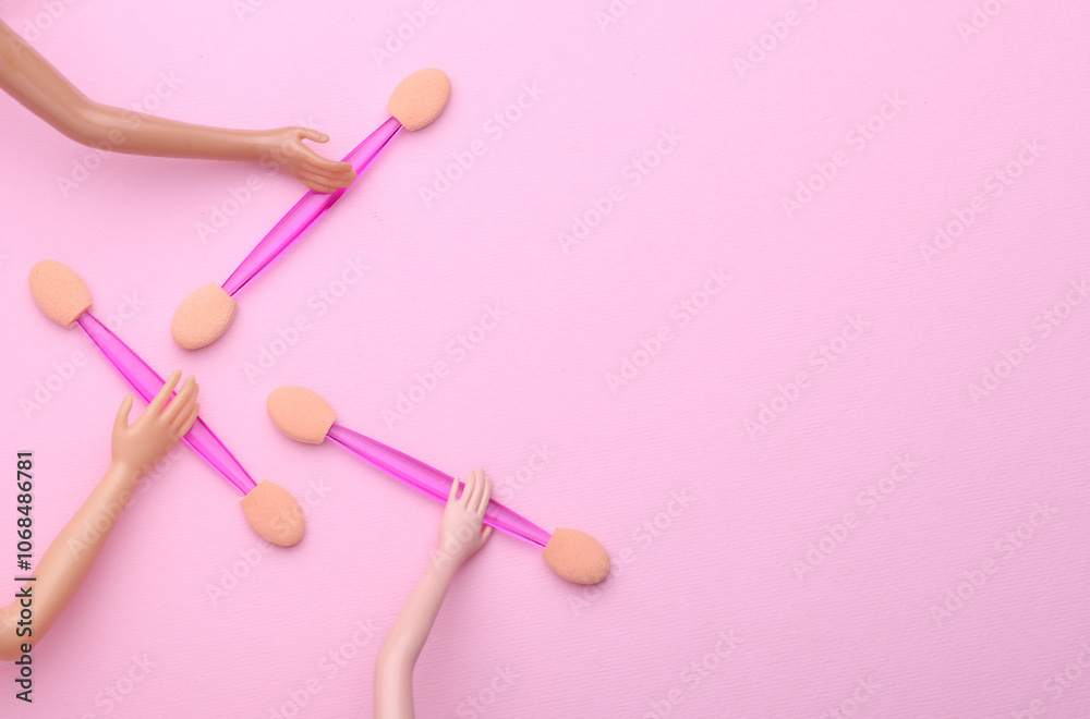 Doll's hands holding makeup sticks on pink background Doll's hands holding makeup sticks on pink background
