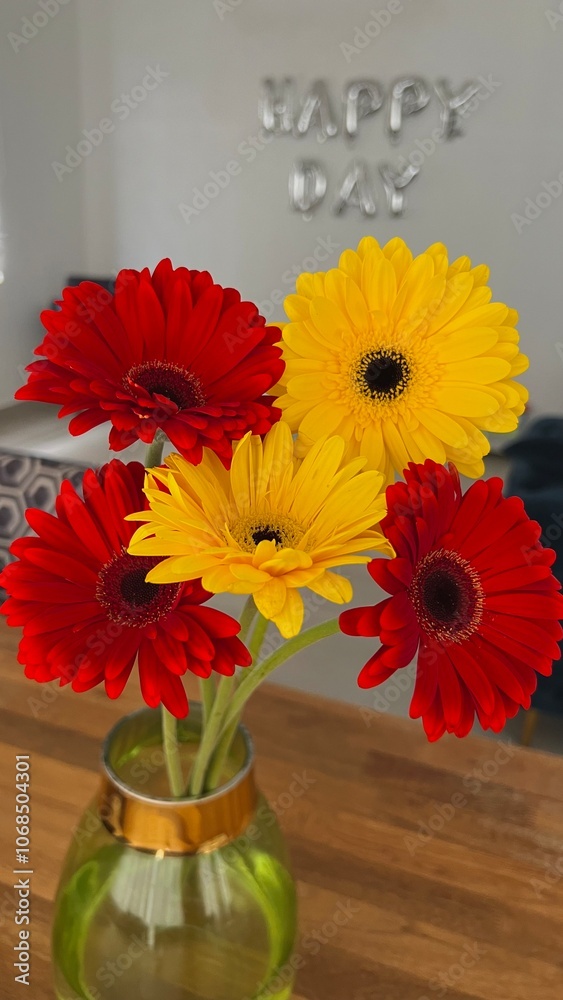 a bouquet of red and yellow gerberas in a glass vase on the background of a wall with the inscription happy day a bouquet of red and yellow gerberas in a glass vase on the background of a wall with the inscription happy day