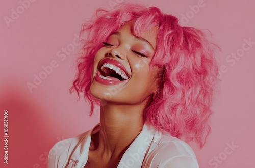 a happy woman with pink hair laughing, against a solid color background.