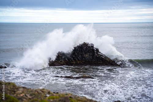 Beautiful nature scene with ocean waves hitting the black rocks of the Icelandic coast