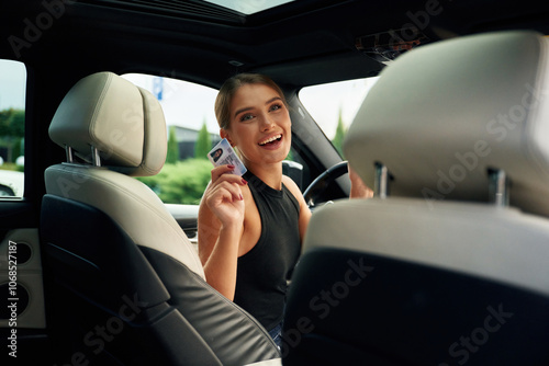 Showing off with the driver's license. Woman is sitting in the car