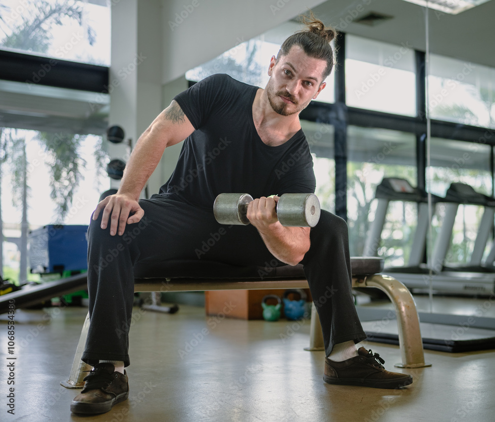 Beautiful athletic muscular man workout strength muscles by one arm lifts dumbbell exercise on bench in fitness gym. Tattoo sport man gains strong physical muscle well body building by weight training