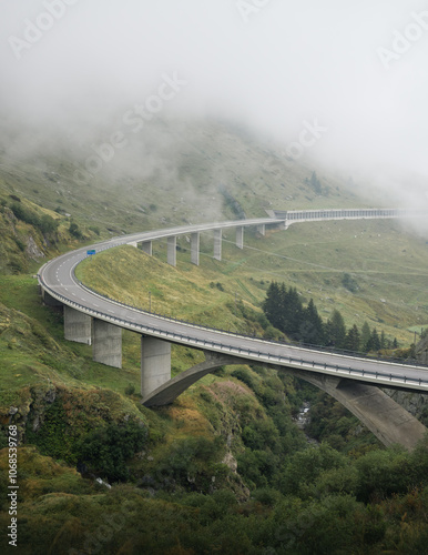 Empty Gotthard Pass on a foggy day. Big curve of highway, green slope of mountain covered in fog in the background. Road in Swiss alps. photo