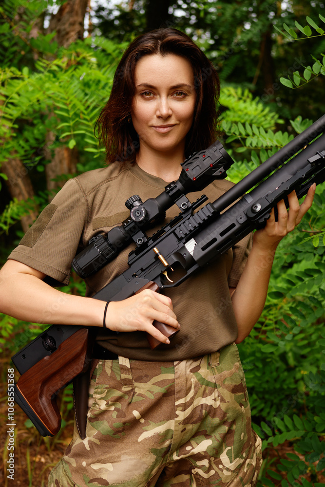 A young woman poses confidently in military attire with a sniper rifle surrounded by dense green foliage during daylight A young woman poses confidently in military attire with a sniper rifle surrounded by dense green foliage during daylight
