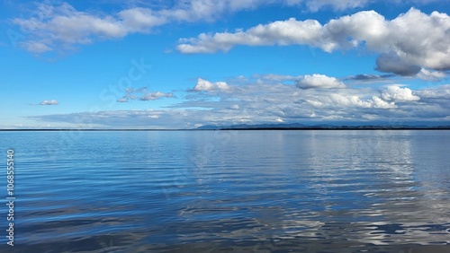 The blue lake merges on the horizon with the sky and white clouds