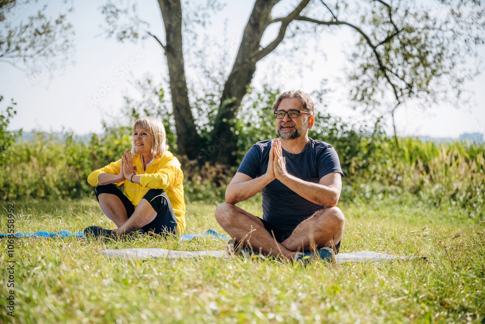 Fototapeta premium Sitting in the lotus pose, meditation. Senior couple together outdoors at nature
