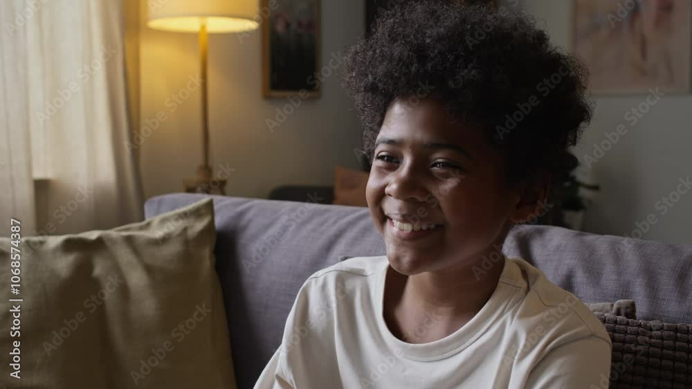 Chest up shot of little African American boy laughing while watching comedy film or cartoon on TV, sitting on sofa and spending free time at home, copy space Chest up shot of little African American boy laughing while watching comedy film or cartoon on TV, sitting on sofa and spending free time at home, copy space