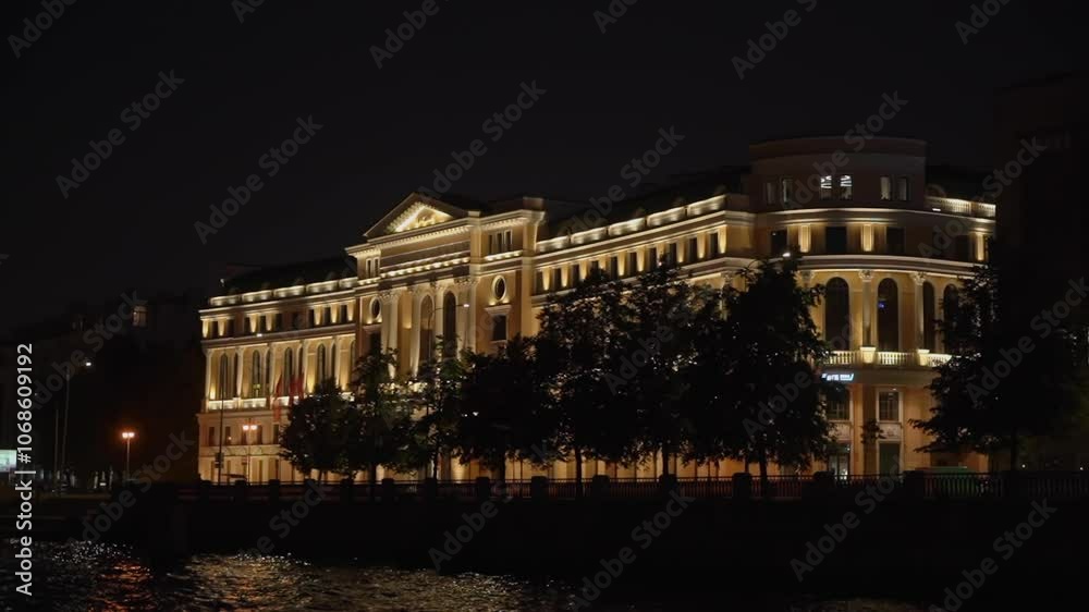 A historic building stands beautifully lit by serene water at night, showcasing stunning architectural charm in Saint-Petersburg A historic building stands beautifully lit by serene water at night, showcasing stunning architectural charm in Saint-Petersburg