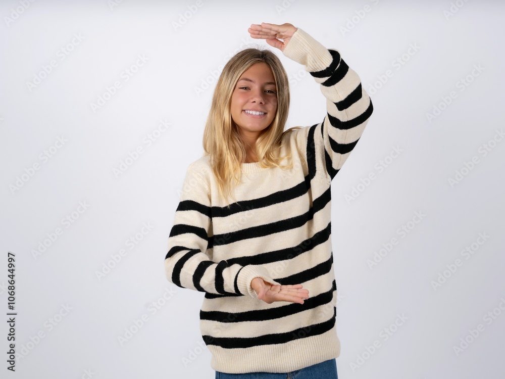 caucasian teen girl wearing striped knitted sweater over white gesturing with hands showing big and large size sign, measure symbol. Smiling looking at the camera. caucasian teen girl wearing striped knitted sweater over white gesturing with hands showing big and large size sign, measure symbol. Smiling looking at the camera.