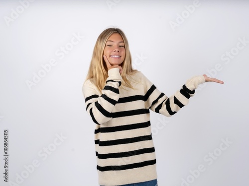 Funny caucasian teen girl wearing striped knitted sweater over white hold open palm new product great proposition