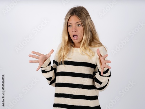 caucasian teen girl wearing striped knitted sweater over white shouts loud, keeps eyes opened and hands tense.