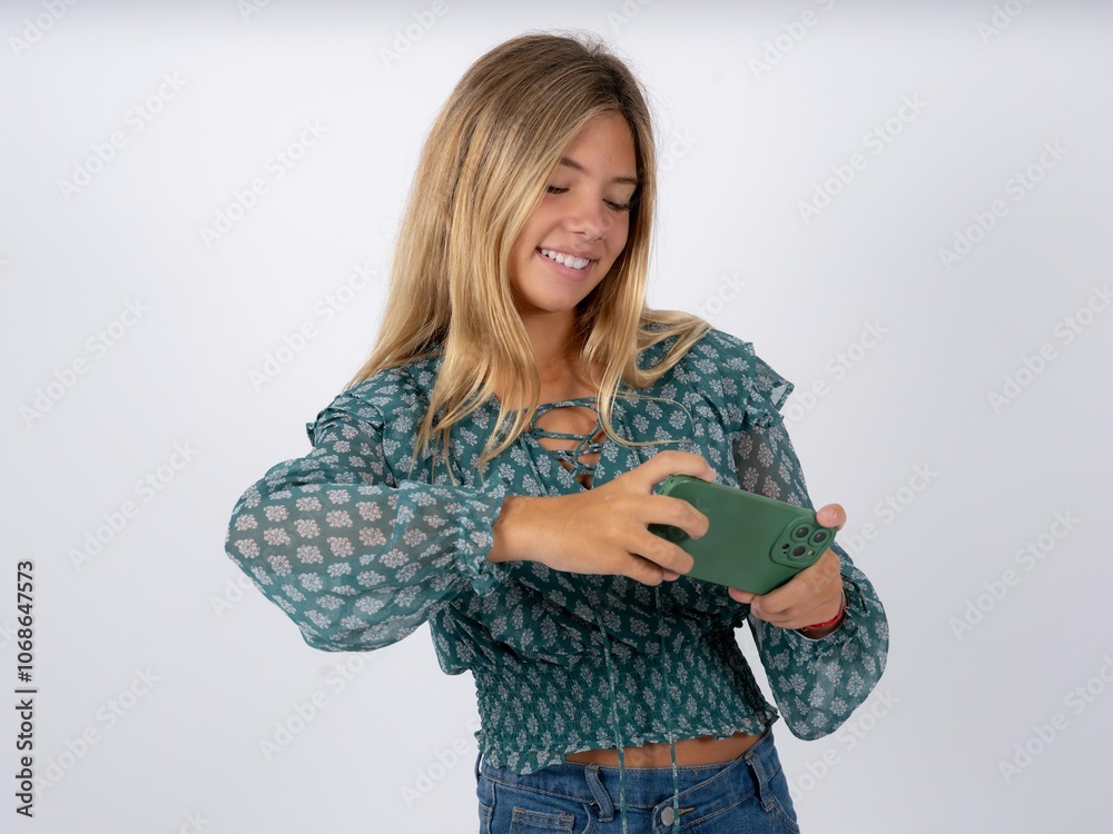 caucasian teen girl wearing green dress over white holding in hands cell playing video games or chatting caucasian teen girl wearing green dress over white holding in hands cell playing video games or chatting