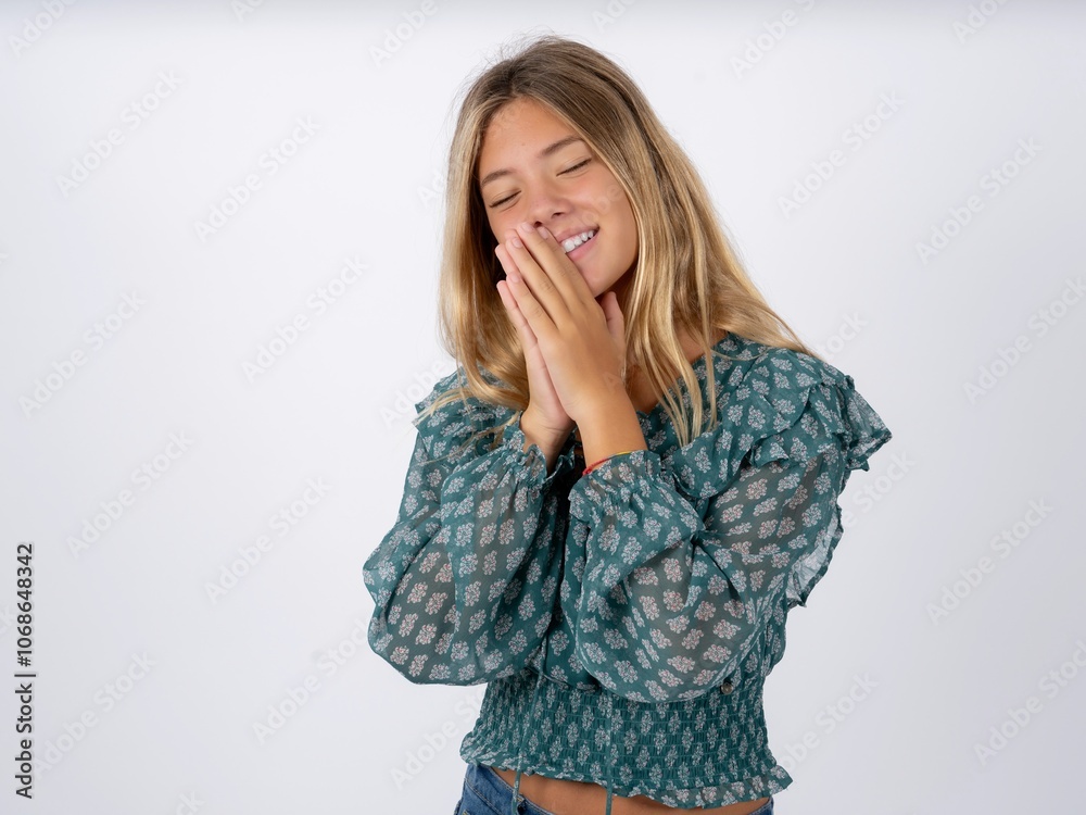 Overjoyed caucasian teen girl wearing green dress over white laughs joyfully and keeps palms pressed together hears something funny Overjoyed caucasian teen girl wearing green dress over white laughs joyfully and keeps palms pressed together hears something funny