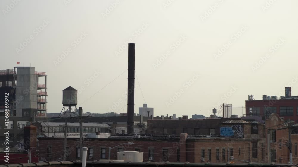 A scenic view of a distinct industrial skyline showcasing a tall chimney and a water tower within an urban environment A scenic view of a distinct industrial skyline showcasing a tall chimney and a water tower within an urban environment