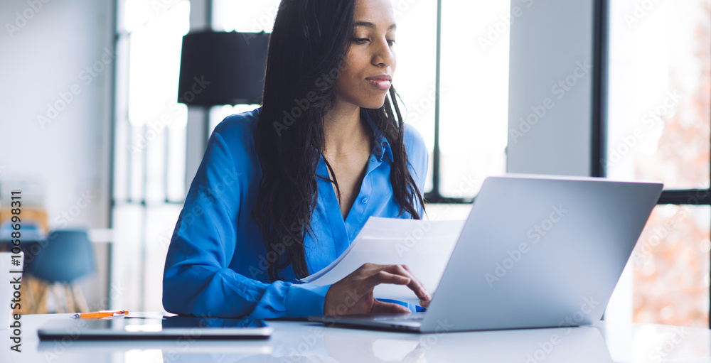 Working black woman viewing typing information from paper Working black woman viewing typing information from paper