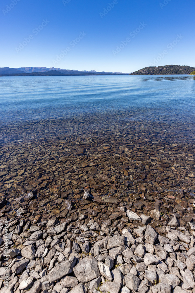 Rocky beach and calm lake on sunny day Rocky beach and calm lake on sunny day