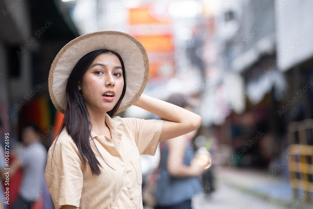 A woman wearing a straw hat is standing on a street