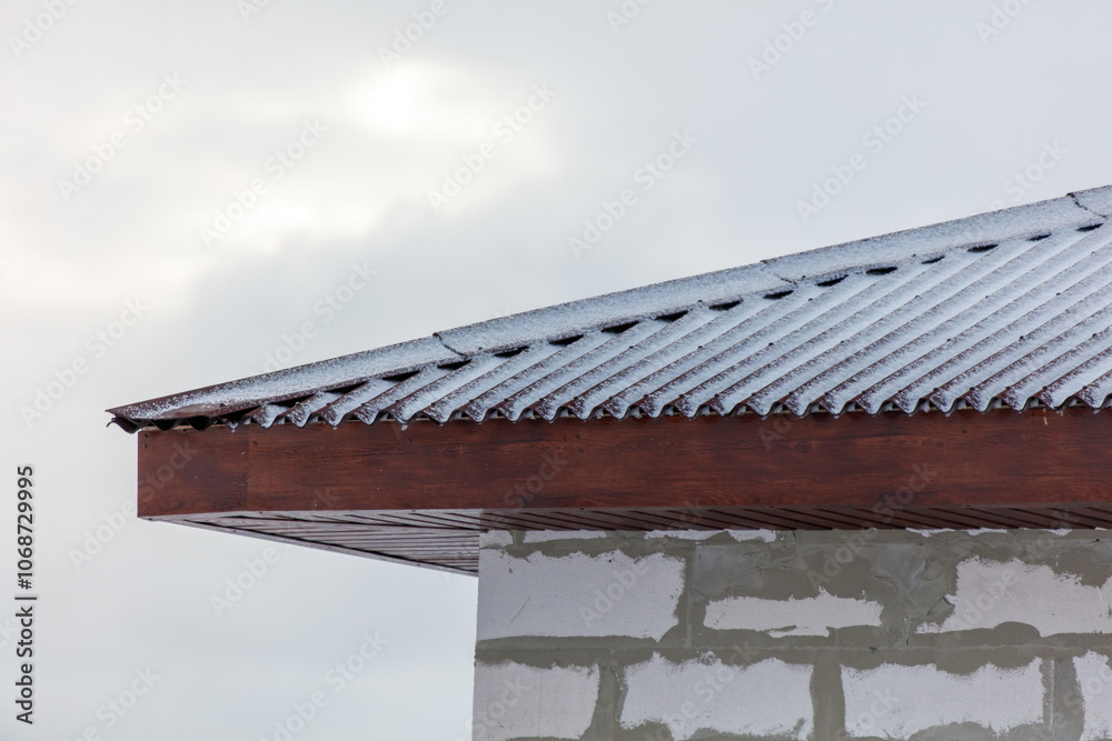 A roof covered in snow and a brick wall A roof covered in snow and a brick wall