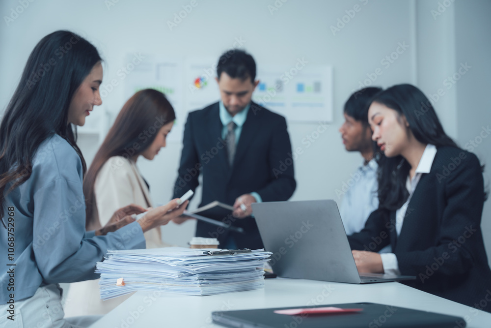 Focused Business Team Meeting: A diverse group of professionals collaborates intensely around a table, laptops and documents spread before them. Focused Business Team Meeting: A diverse group of professionals collaborates intensely around a table, laptops and documents spread before them.