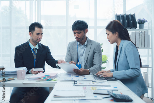 Strategic Business Meeting: Focused team collaboration. Diverse business professionals analyzing data and documents during a serious meeting in a modern office setting. 