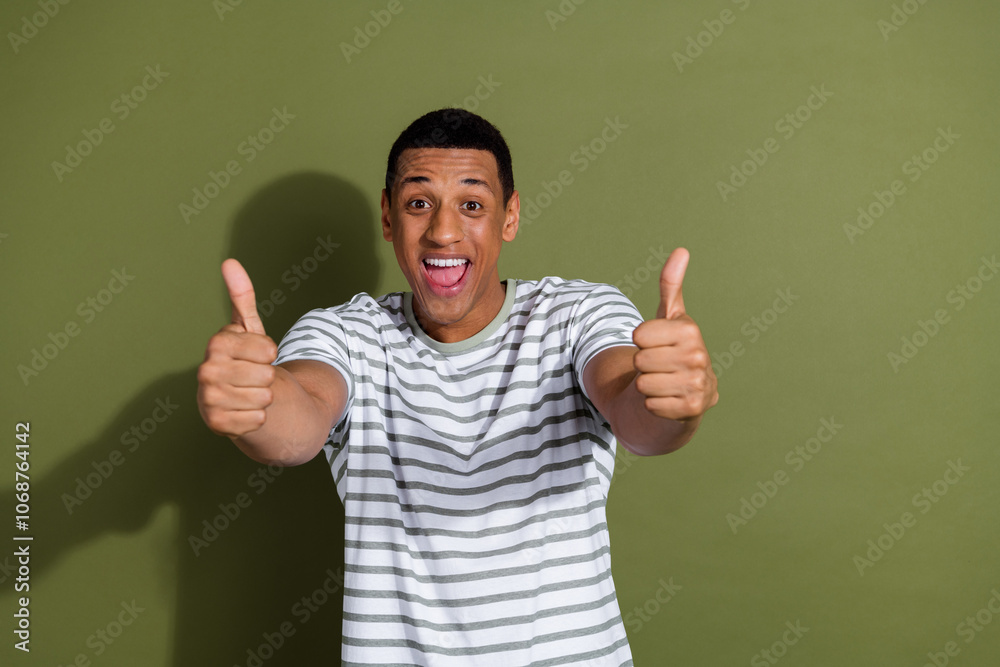Naklejka premium Photo portrait of nice young male excited thumb up wear trendy striped white outfit isolated on khaki color background
