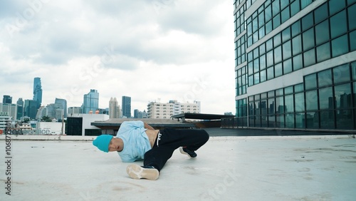 Stylish caucasian dancing man performing break dance at skyscraper. Portrait image of young happy man practicing street dance performance choreographer in modern urban city. Paris style. Hiphop. photo