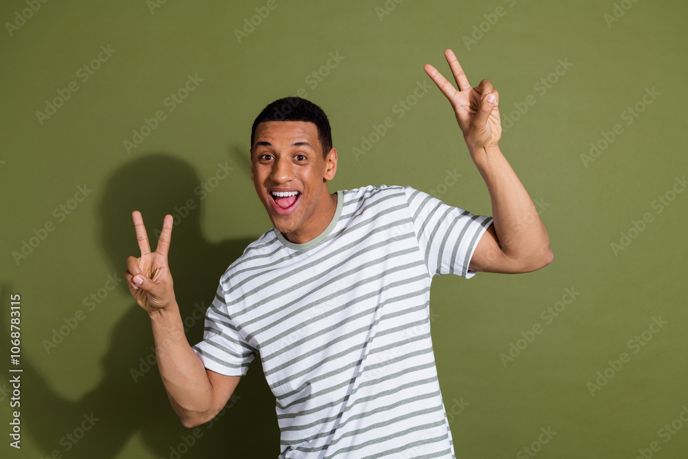 Fototapeta premium Photo portrait of attractive young man show v-sign dressed stylish striped white clothes isolated on khaki color background