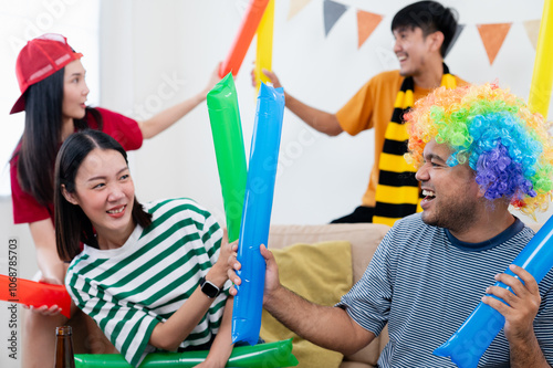 Group of Asian male and female friends Watch the World Cup live broadcast on TV. Sports fans shout and hi five together, celebrating the sports team's victory. and eat snacks together at home photo