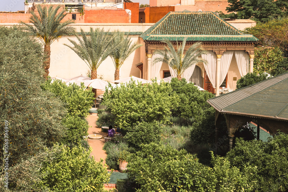 Obraz premium Garden path through a beautiful lush green botanical garden with tropical plants and palm trees, traditional moroccan architecture at famous destination in Marrakech, Le Jardin Secret, Morocco