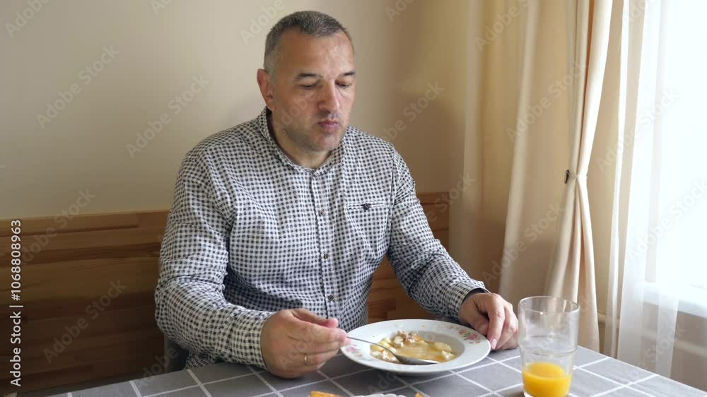 A man is sitting at the table and eating soup. A man is sitting at the table and eating soup.