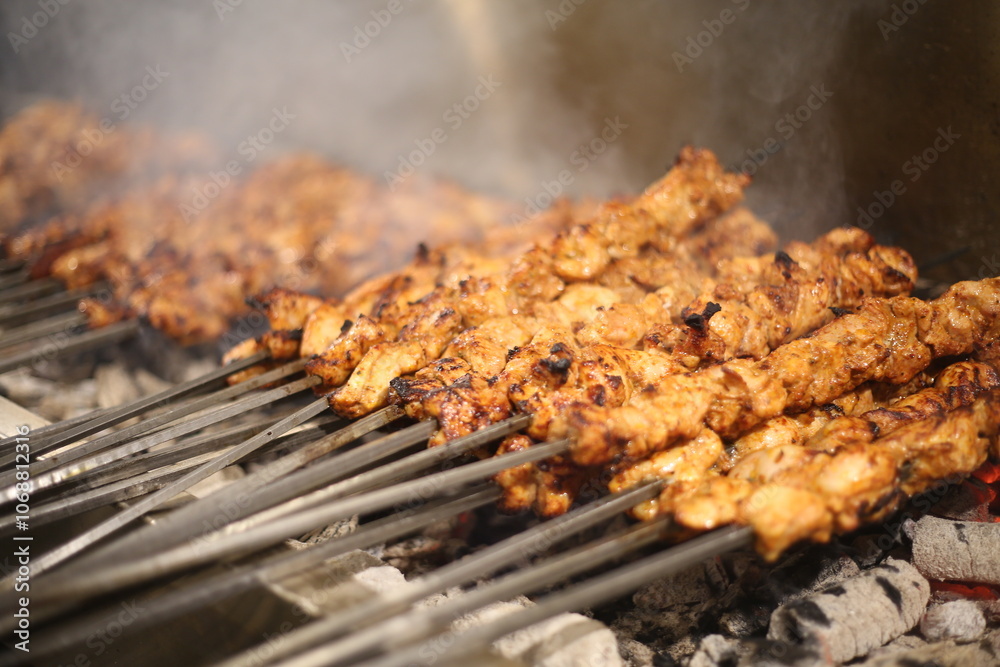 Close-up of grilled chicken skewers cooking over hot charcoal, emitting smoky aroma. Juicy, marinated meat skewers with charred edges, showcasing traditional barbecue grilling technique Close-up of grilled chicken skewers cooking over hot charcoal, emitting smoky aroma. Juicy, marinated meat skewers with charred edges, showcasing traditional barbecue grilling technique