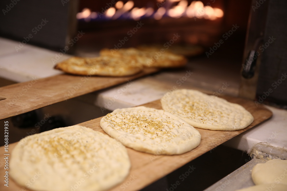 Artisan Baker Placing Fresh Pide Dough on a Wooden Peel Before Baking in a Stone Oven