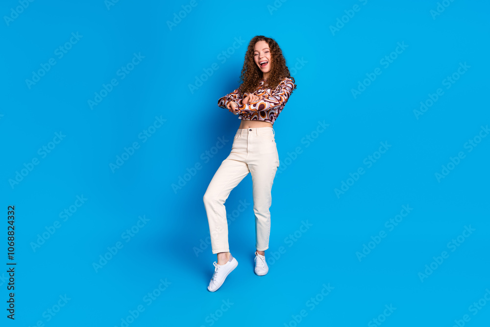 Full size photo of pretty young girl dancing enjoy disco wear trendy colorful outfit isolated on blue color background Full size photo of pretty young girl dancing enjoy disco wear trendy colorful outfit isolated on blue color background