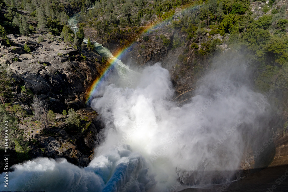 An explosive discharge of water from the O'Shaughnessy Dam into the Tuolumne River in Hetch Hetchy, Yosemite NP, and a rainbow forms above the river as sunlight passes through the mist. Horizontal An explosive discharge of water from the O'Shaughnessy Dam into the Tuolumne River in Hetch Hetchy, Yosemite NP, and a rainbow forms above the river as sunlight passes through the mist. Horizontal
