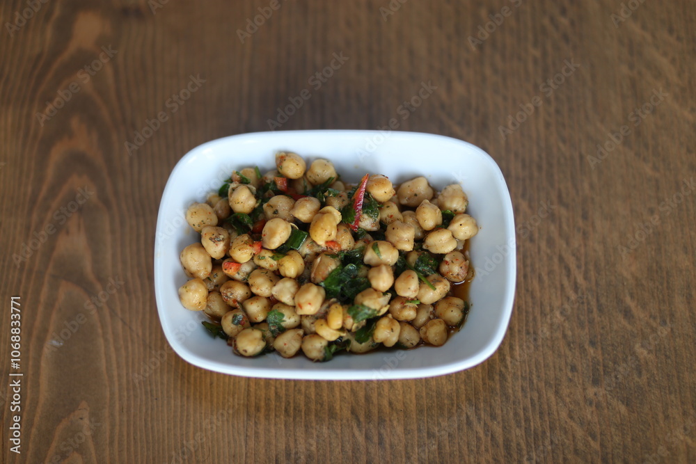 A close-up of a delicious and healthy Turkish appetizer, featuring roasted chickpeas with herbs and spices, served in a white bowl A close-up of a delicious and healthy Turkish appetizer, featuring roasted chickpeas with herbs and spices, served in a white bowl