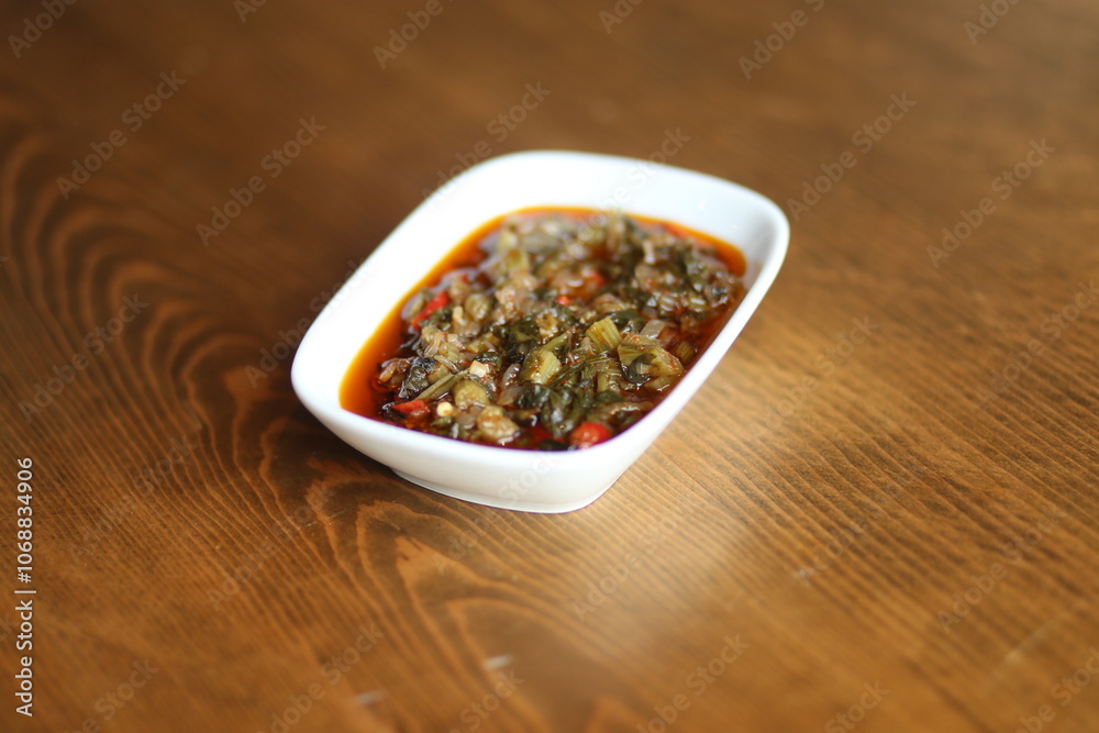 A close-up of a traditional Turkish appetizer, közlenmiş biber salçası, served in a white bowl on a wooden table A close-up of a traditional Turkish appetizer, közlenmiş biber salçası, served in a white bowl on a wooden table