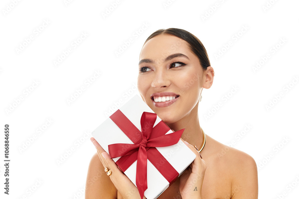 A young woman smiles radiantly while holding a luxurious gift wrapped with a bright bow. A young woman smiles radiantly while holding a luxurious gift wrapped with a bright bow.