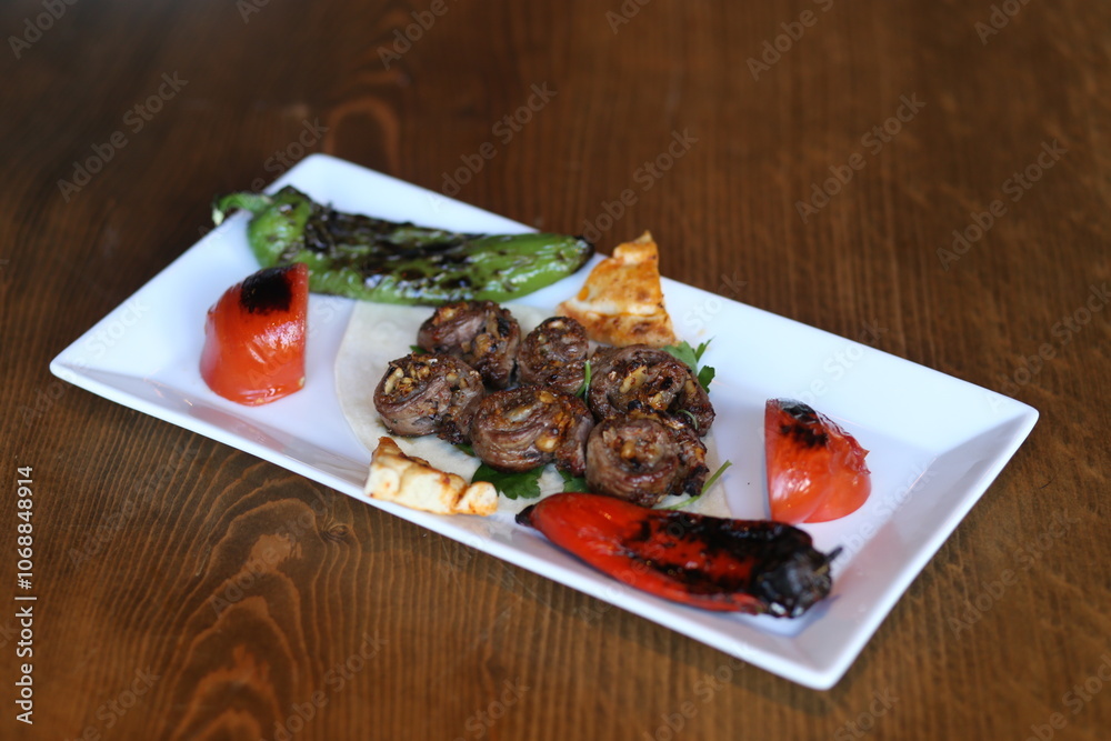 A sizzling platter of grilled Kofte kebabs, served with fresh peppers, tomatoes, and a drizzle of olive oil A sizzling platter of grilled Kofte kebabs, served with fresh peppers, tomatoes, and a drizzle of olive oil