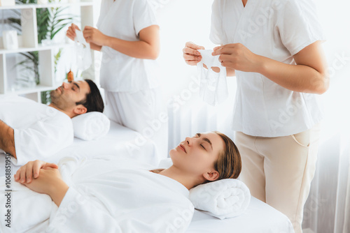 Serene modern daylight ambiance of spa salon, couple customer indulges in rejuvenating with facial skincare mask. Facial skin treatment and beauty cosmetology procedure for face. Quiescent