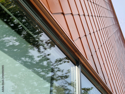 bronze tiles lining the walls of the house, squares similar to fish scales. shiny luxury. modern industrial building with windows gray frames. scaffolding with ladder