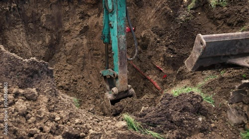 Construction workers operate heavy machinery to dig deep in a rural location, revealing buried utilities. The team