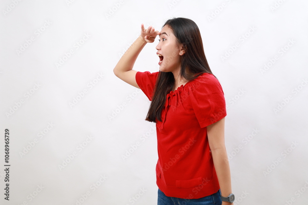 Young woman wearing casual red shirt very happy and smiling looking far away with hand over head. searching concept. Young woman wearing casual red shirt very happy and smiling looking far away with hand over head. searching concept.