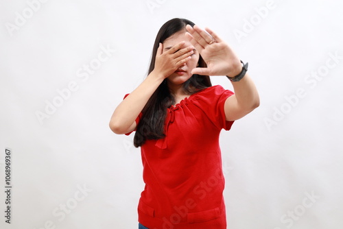 Young hispanic woman wearing casual red shirt covering eyes with hands and doing stop gesture with sad and fear expression. embarrassed and negative concept.