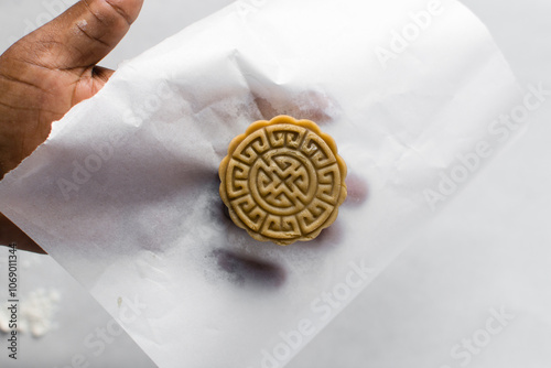 Overhead view of homemade mooncakes, top view of raw mooncakes on white parchment paper, process of making mooncakes for Lunar New Year