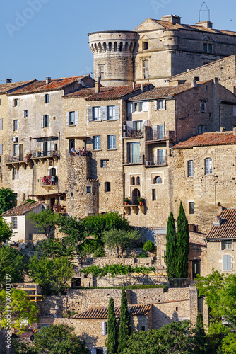 GORDES, PROVENCE, FRANCE - JULY 7, 2012:  stone facades of luxury holiday homes, warm late afternoon sunlight, people relaxing on balconies, detail shot of one of the most beautiful villages in France