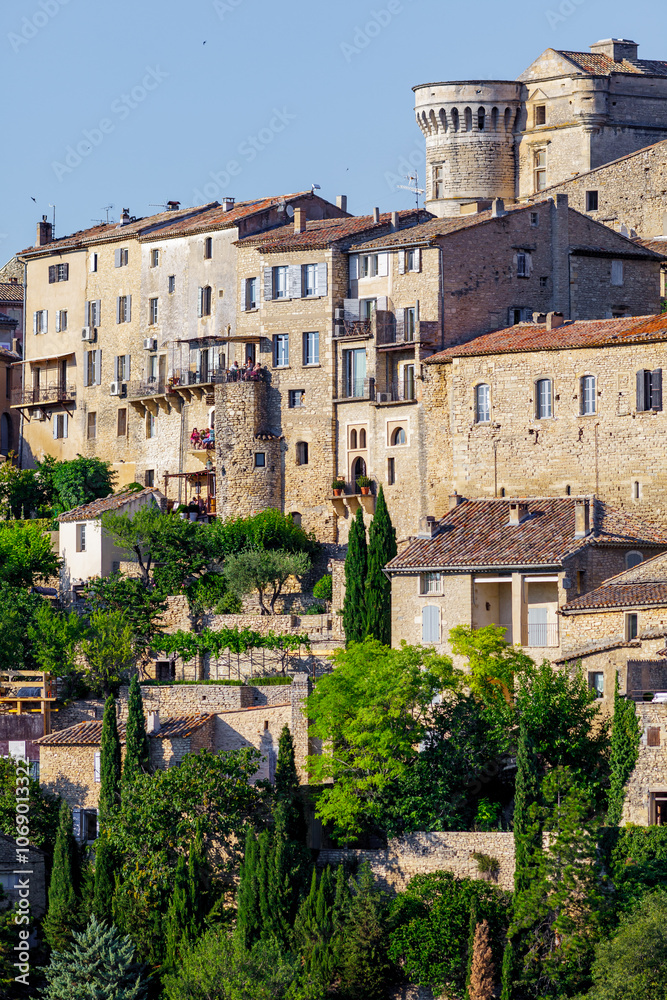GORDES, PROVENCE, FRANCE: stone facades of luxury holiday homes, warm late afternoon sunlight, with balconies and terracotta roof tiles, detail shot of one of the most beautiful villages in France GORDES, PROVENCE, FRANCE: stone facades of luxury holiday homes, warm late afternoon sunlight, with balconies and terracotta roof tiles, detail shot of one of the most beautiful villages in France