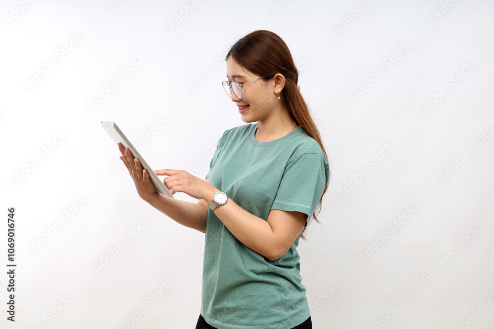 Smiling busy young asian college student woman using tablet computer, happy student woman in casual looking at tab device analyzing her data standing over white background Smiling busy young asian college student woman using tablet computer, happy student woman in casual looking at tab device analyzing her data standing over white background