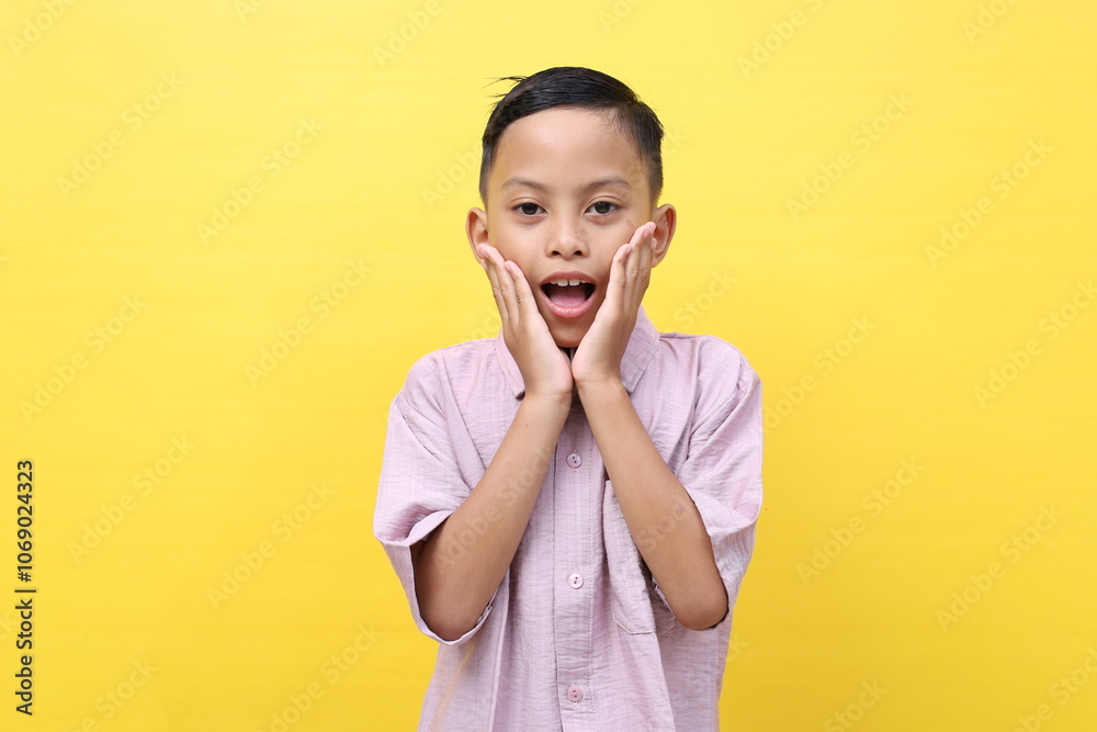 Surprise asian schoolboy gesture standing while shouting and looking at the camera. Isolated on yellow Surprise asian schoolboy gesture standing while shouting and looking at the camera. Isolated on yellow