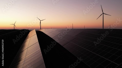 Solar panels park and wind turbines at sunset.Windmill turbines generating green energy electric.Green energy reduce carbon emissions and makes earth cleaner and more ecological.	
